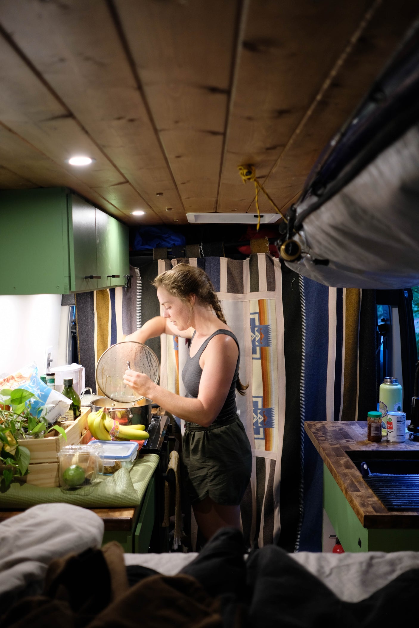 Woman cooks in her RV rental kitchen, showcasing the compact yet functional setup for meals on the go inside a camper van.