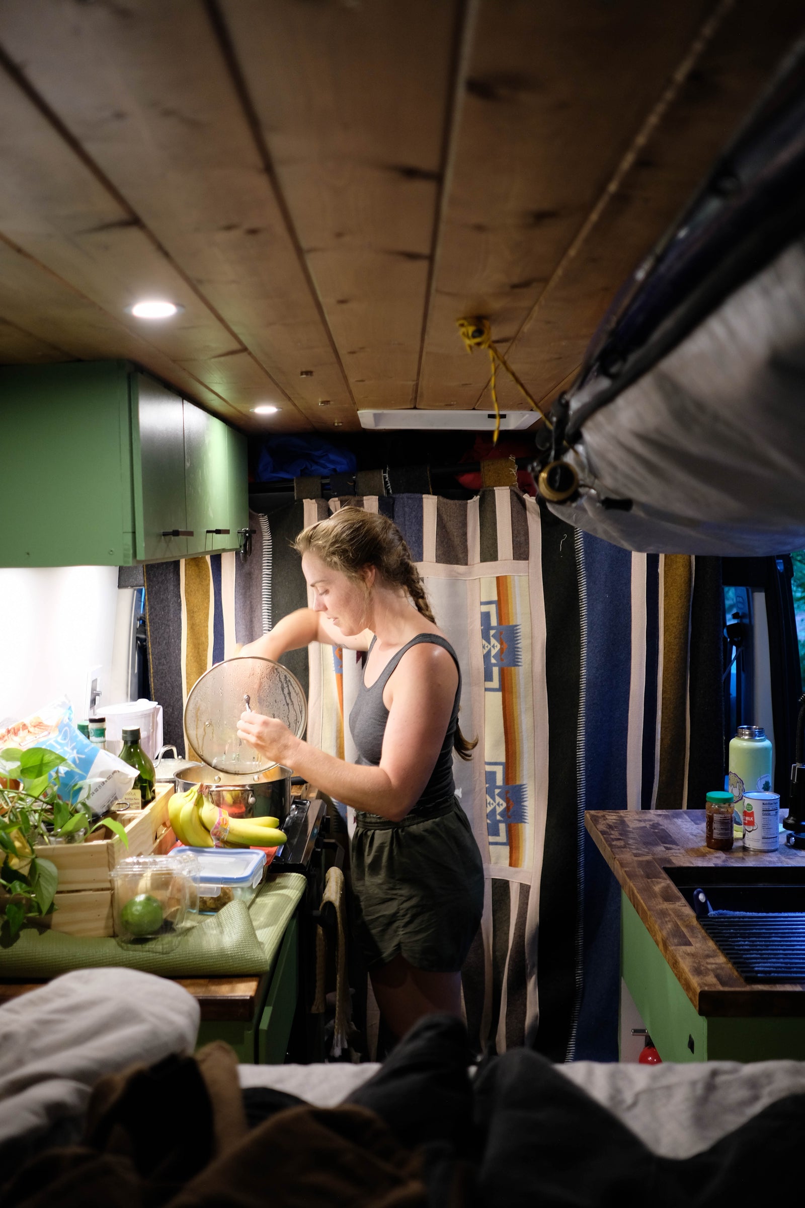 Woman cooks in her RV rental kitchen, showcasing the compact yet functional setup for meals on the go inside a camper van.