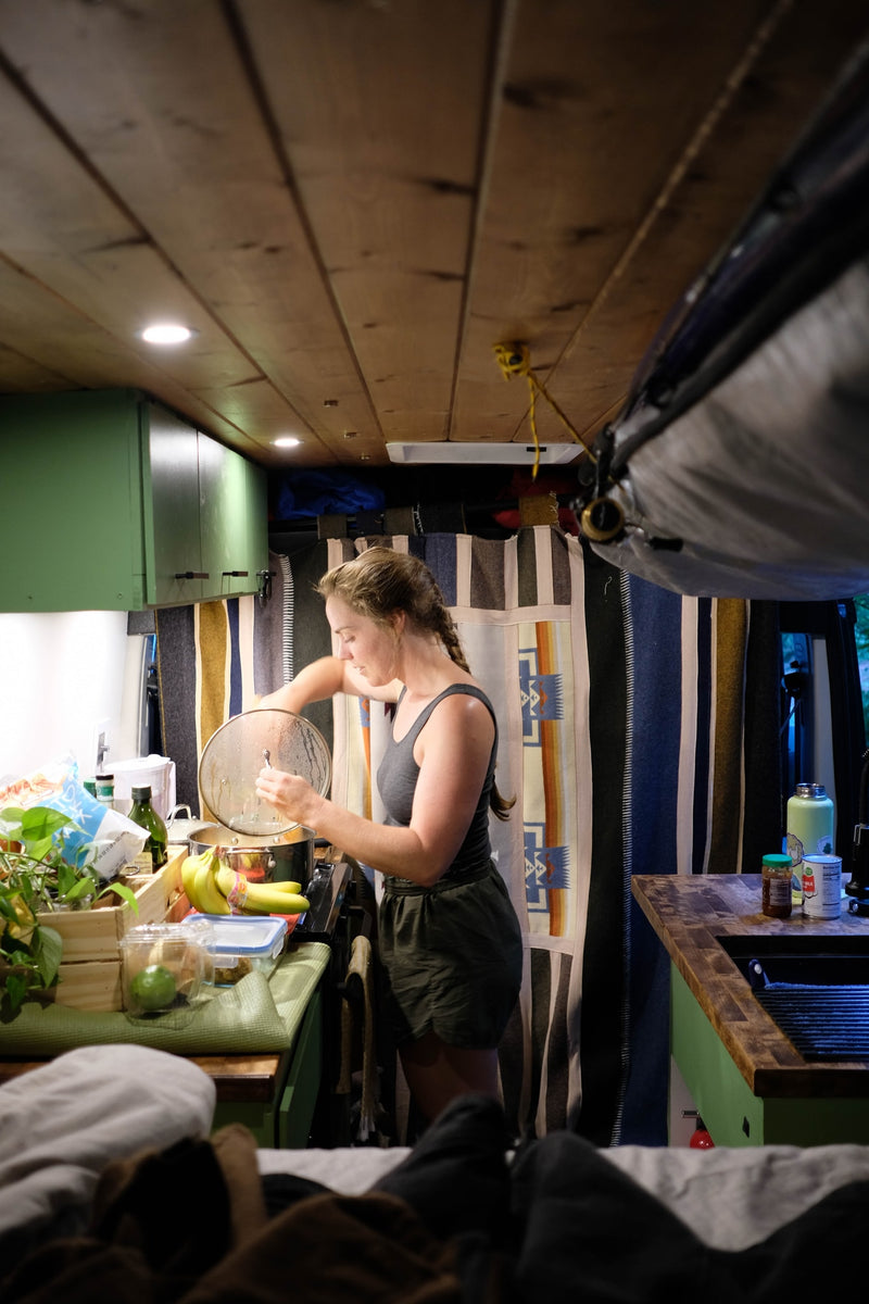 Woman cooks in her RV rental kitchen, showcasing the compact yet functional setup for meals on the go inside a camper van. — photo 7