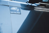 Close-up of a modern RV rental featuring a 'SKYBUNK™' emblem, indicating an elevated bed, with bright LED side lights.