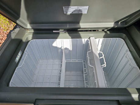Empty Truma portable fridge/cooler, perfect for your RV rental trip. Interior features wire baskets & LED lighting, ready for provisions.