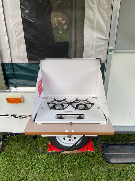 An outdoor stove attached to a pop-up camper RV rental, perfect for campsite cooking.