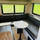 Cozy RV rental dinette: U-shaped seating, round table, and windows offer a comfortable spot for travel and meals.