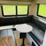 Cozy RV rental dinette: U-shaped seating, round table, and windows offer a comfortable spot for travel and meals. — photo 15
