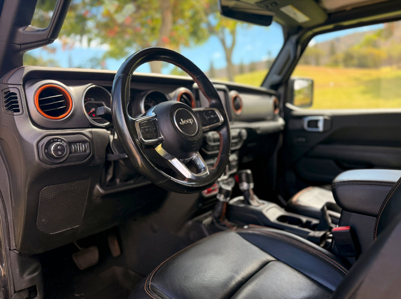 Driver's view inside a modern Jeep. Black leather seats with orange stitching and accents. Great for exploring, or as an alternative to an rv rental.