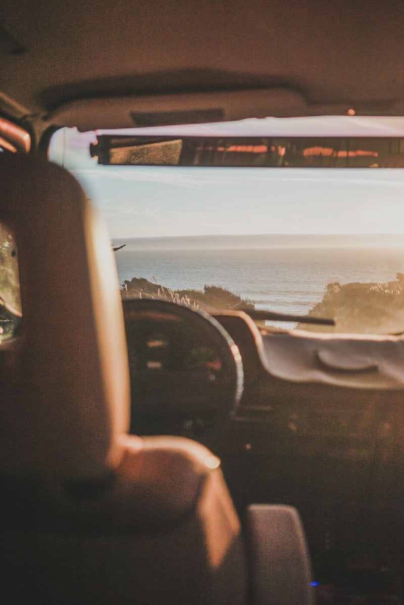  and a bright ocean sunset view from the rear.|View from an RV rental dashboard showing a sunlit ocean and coastline. Interior seat on left — photo 7