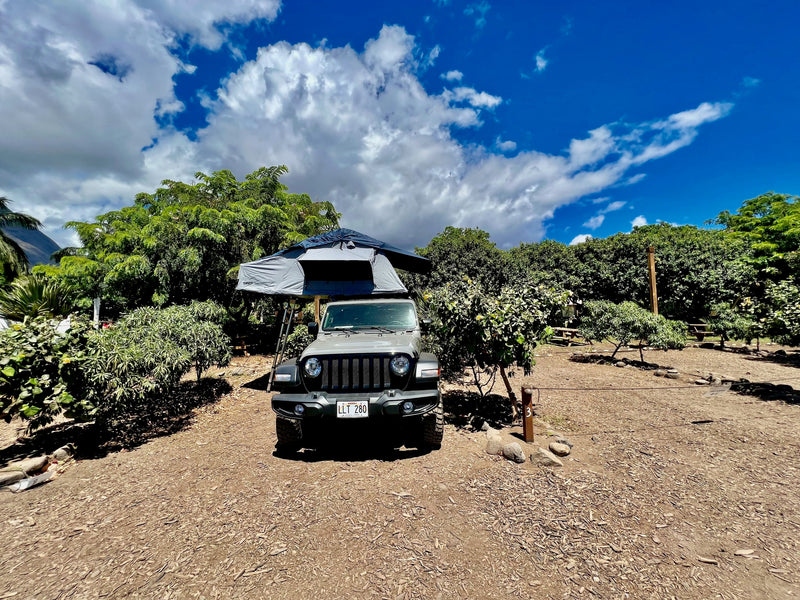 Gray Jeep Wrangler with a Thule rooftop tent, perfect for an RV rental adventure in a lush Hawaii campsite. — photo 3