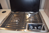 RV rental kitchen: Dometic stainless steel gas stovetop with two burners, controls, and a wireless charger on the counter.