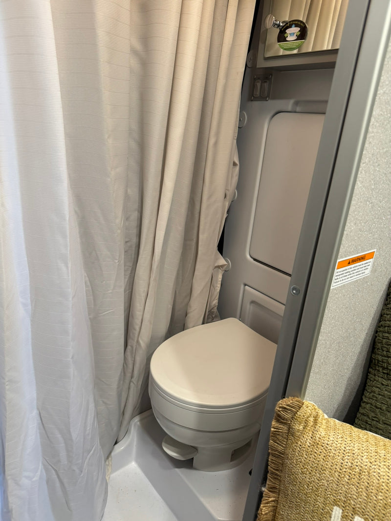 and overhead storage create a comfortable travel space.|This compact RV rental bathroom features a sink — photo 6