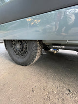 Low-angle view of an RV rental. Features a Black Rhino wheel & ROAMBUILT undercarriage water system with spigot.