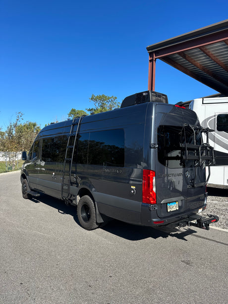 Explore in this dark grey Mercedes Sprinter camper van, perfect for your next rv rental adventure. Features ladder, AC, bike rack.