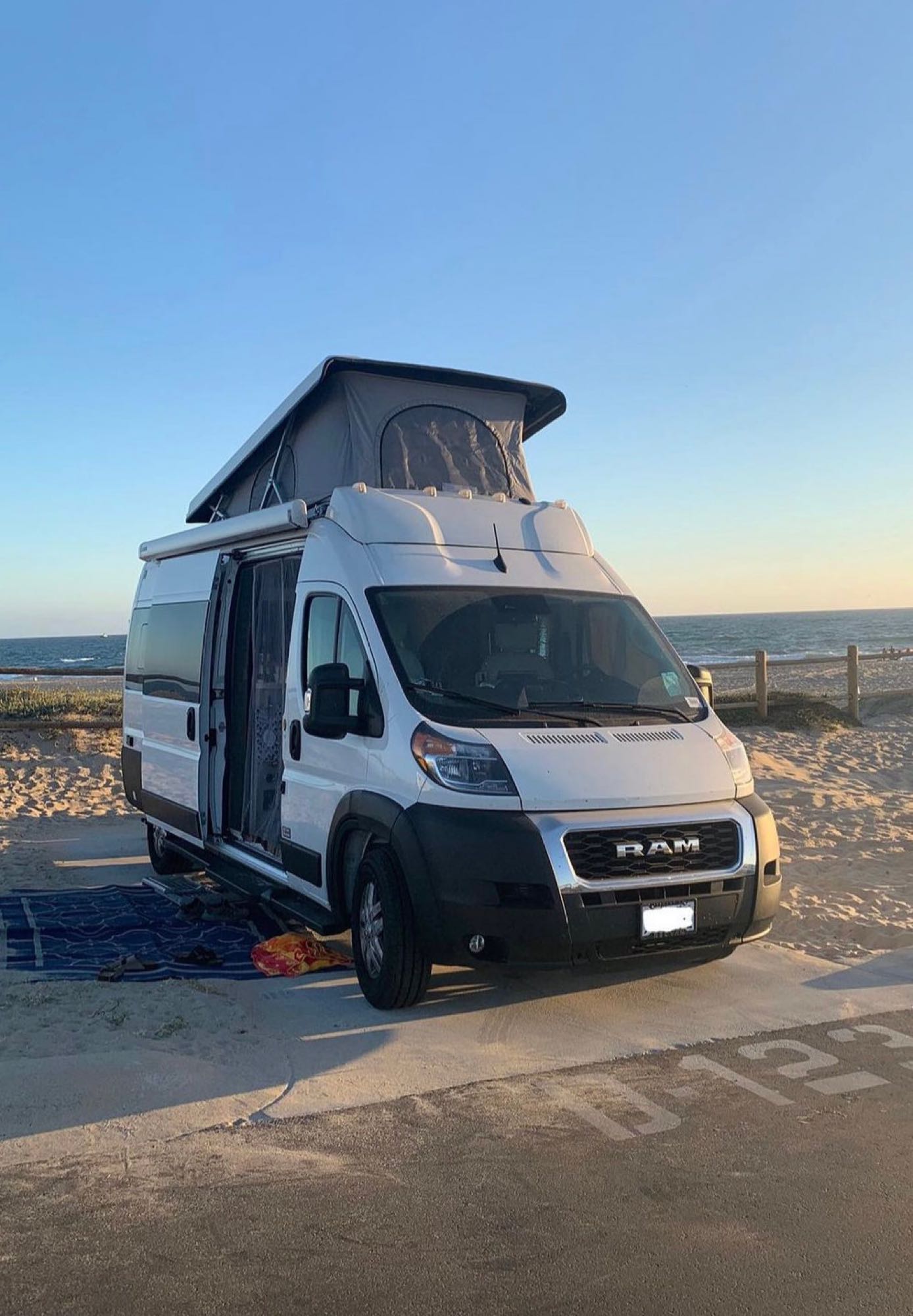  is parked on a driveway with its door open.|This RV rental is parked at a sunny desert campsite — photo 4