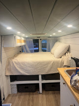 Experience van life in this cozy rv rental! Features a comfortable bed, kitchen area, and organized storage inside.
