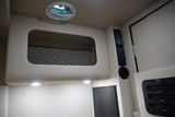 Inside an RV rental: organized overhead storage with netting, ceiling vent, LED lights, and stylish black air vents.