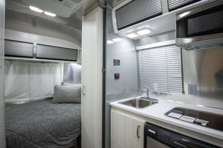  and inviting dining area with bench seating.|Bright RV rental interior showing a kitchen with stainless fridge — photo 6