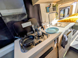 This RV rental's efficient kitchenette includes a stovetop, sink, and tools like a moka pot and pan, perfect for travel cooking.