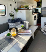 Cozy rv rental with dining table, juice, and a 'Best Day Hikes' book. Kitchen & beach view for your travel adventures.