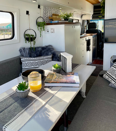 Cozy rv rental with dining table, juice, and a 'Best Day Hikes' book. Kitchen & beach view for your travel adventures.