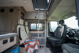 RV rental interior: ladder to pop-top, dinette area with patterned blanket, cockpit, and scenic mountain views.