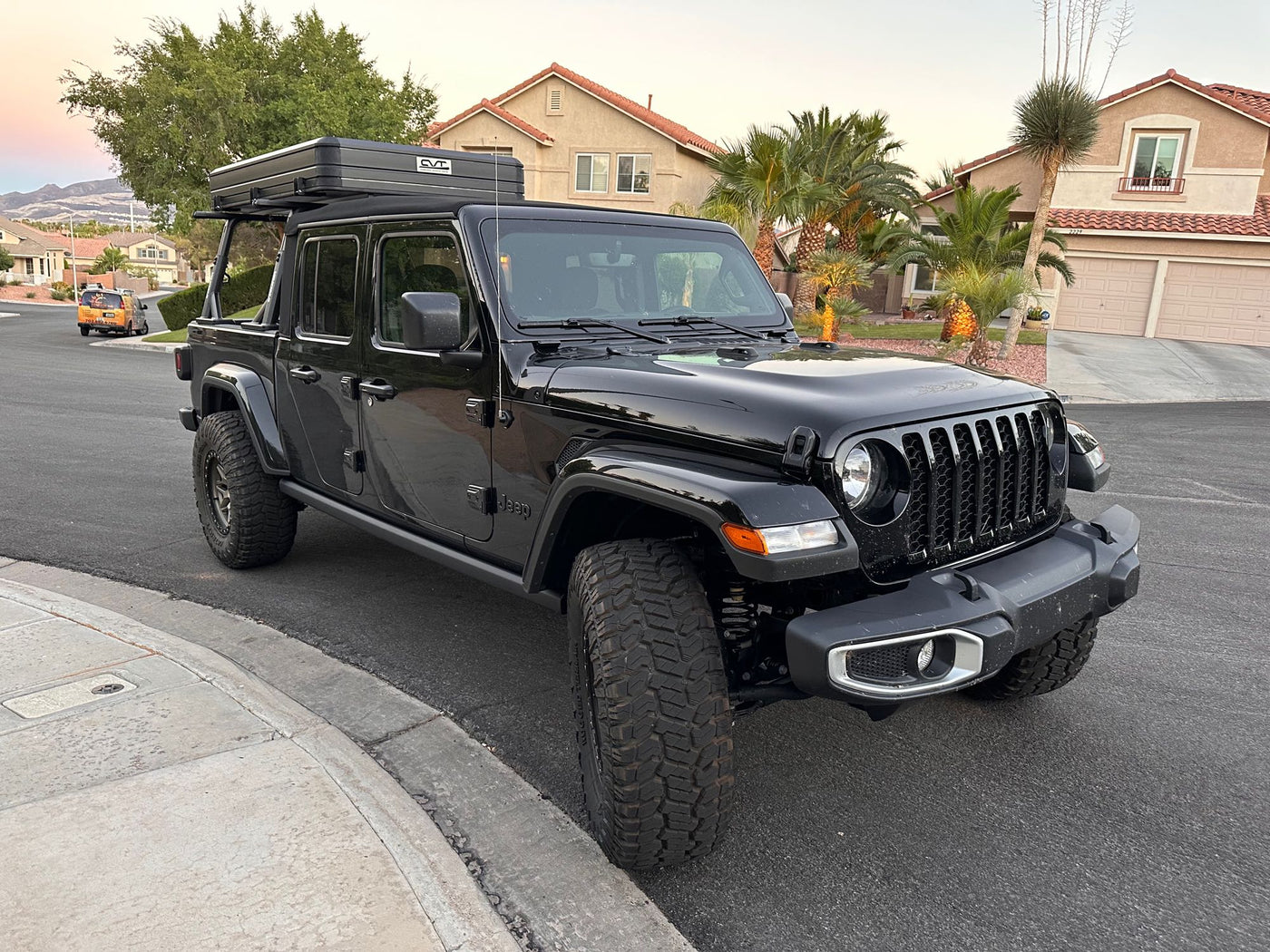 Black Jeep Gladiator truck with a hard-shell roof-top tent, parked curbside. A versatile rv rental alternative! — photo 3