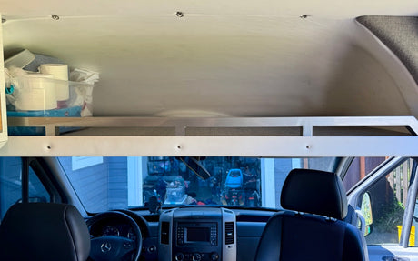 Inside a tidy rv rental: the front cabin, dashboard, and overhead storage with essential supplies.