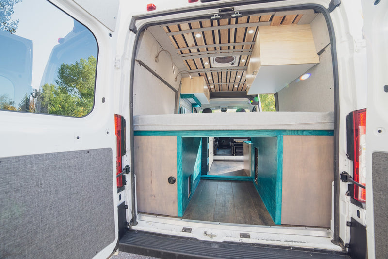 Inside a custom camper van, ideal for rv rental: elevated bed, under-bed storage, wood slat ceiling. Ready for adventure. — photo 8