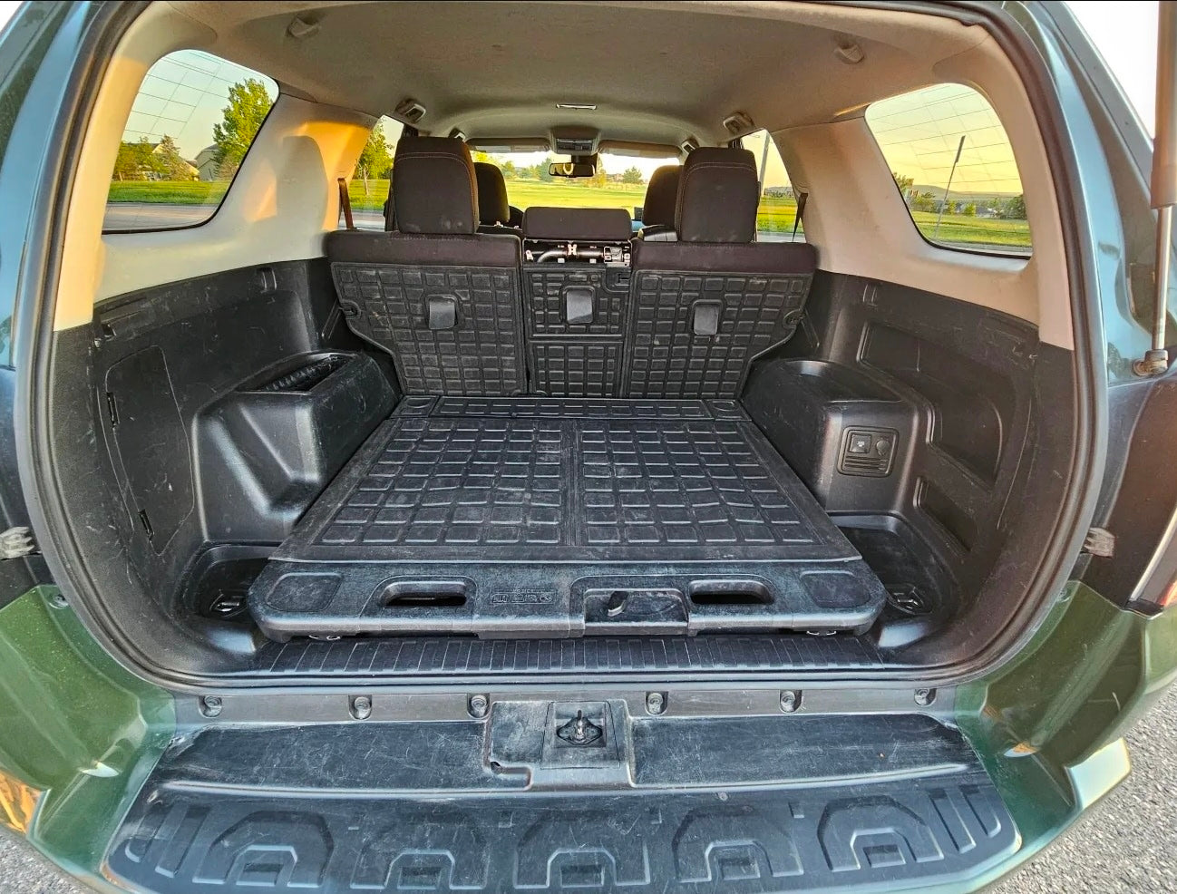 Spacious SUV cargo area, ideal for an RV rental adventure. Features a durable rubber mat and sliding tray for organized travel storage.