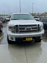 A white Ford F-150 pickup truck, ideal for towing an RV rental, parked on wet pavement on a rainy day.