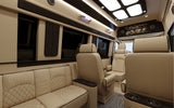 Step into this luxury RV rental's spacious interior with cream leather seating, a TV, wood accents, and ambient lighting.