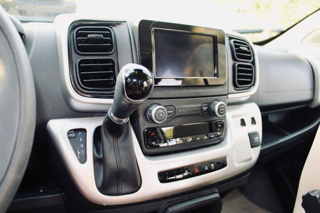 RV rental interior: dashboard with automatic gear shifter, touchscreen display, and climate controls. A clear view for your adventure.