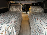Cozy RV rental interior with two narrow beds featuring ski-themed bedding, ready for adventure.