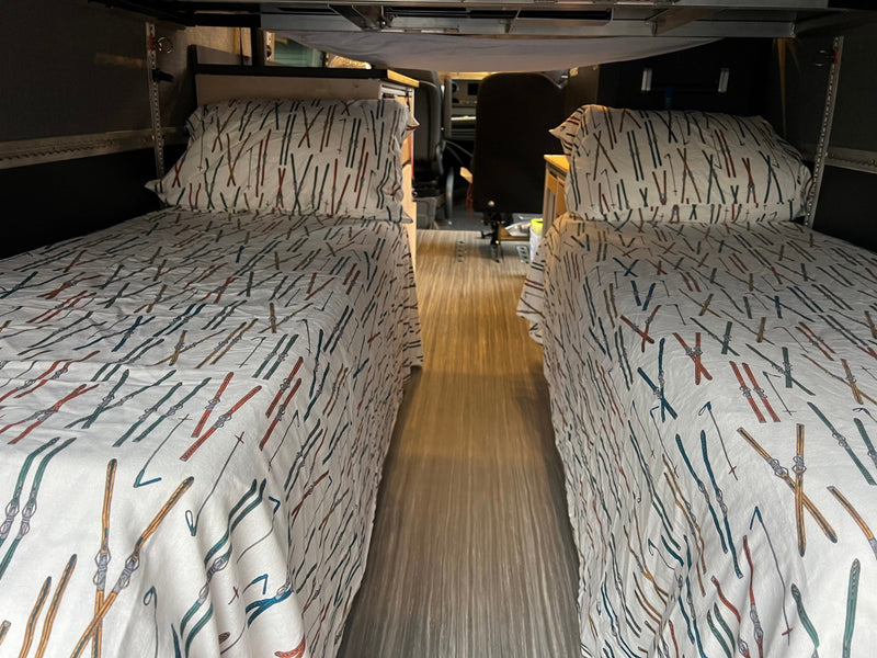 Cozy RV rental interior with two narrow beds featuring ski-themed bedding, ready for adventure. — photo 15