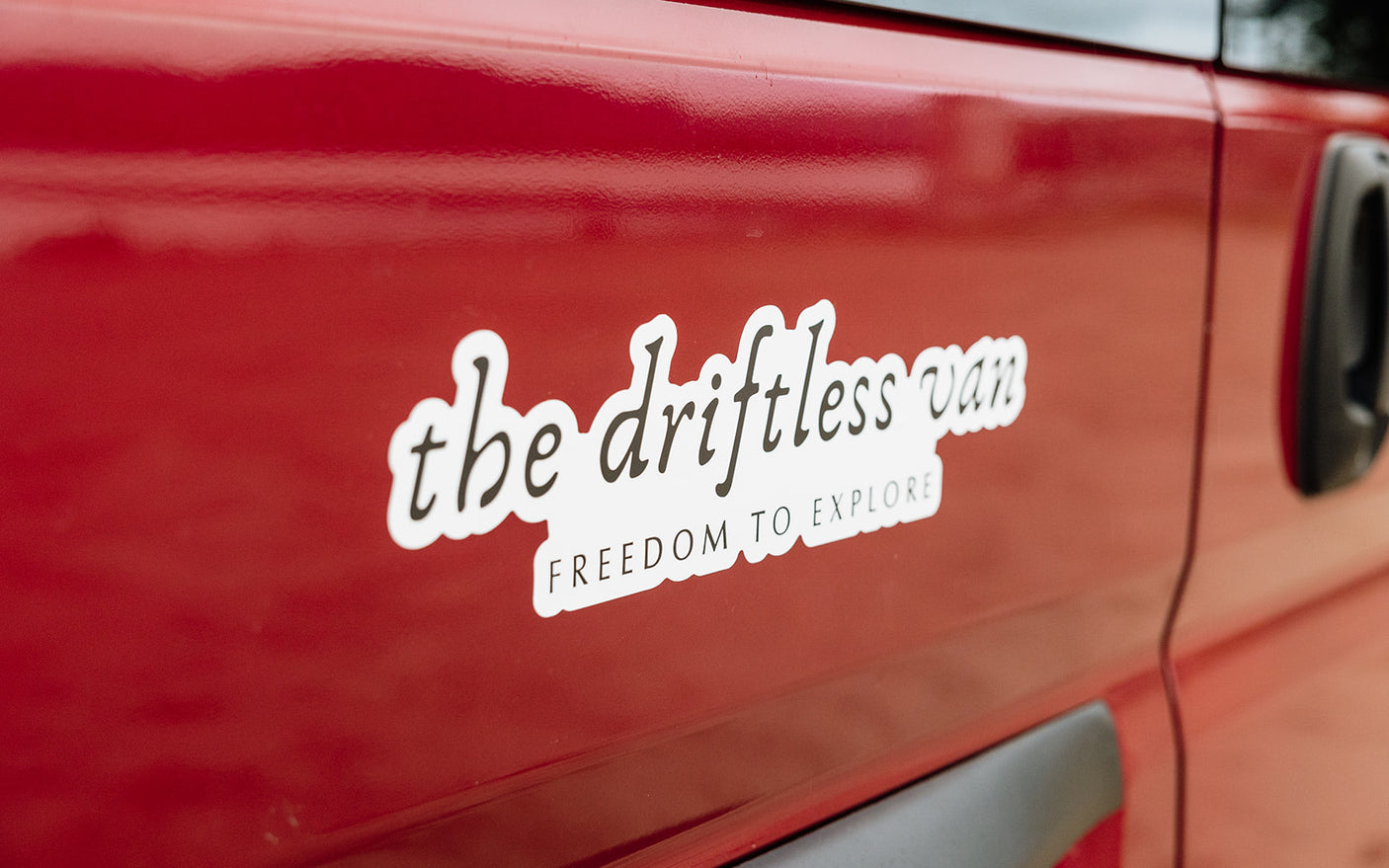 Red RV rental van featuring "the driftless van" sticker: "FREEDOM TO EXPLORE". Ready for your next adventure.