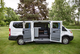 This white camper van, ideal for rv rental, reveals its custom interior with opened side doors on a grassy field.