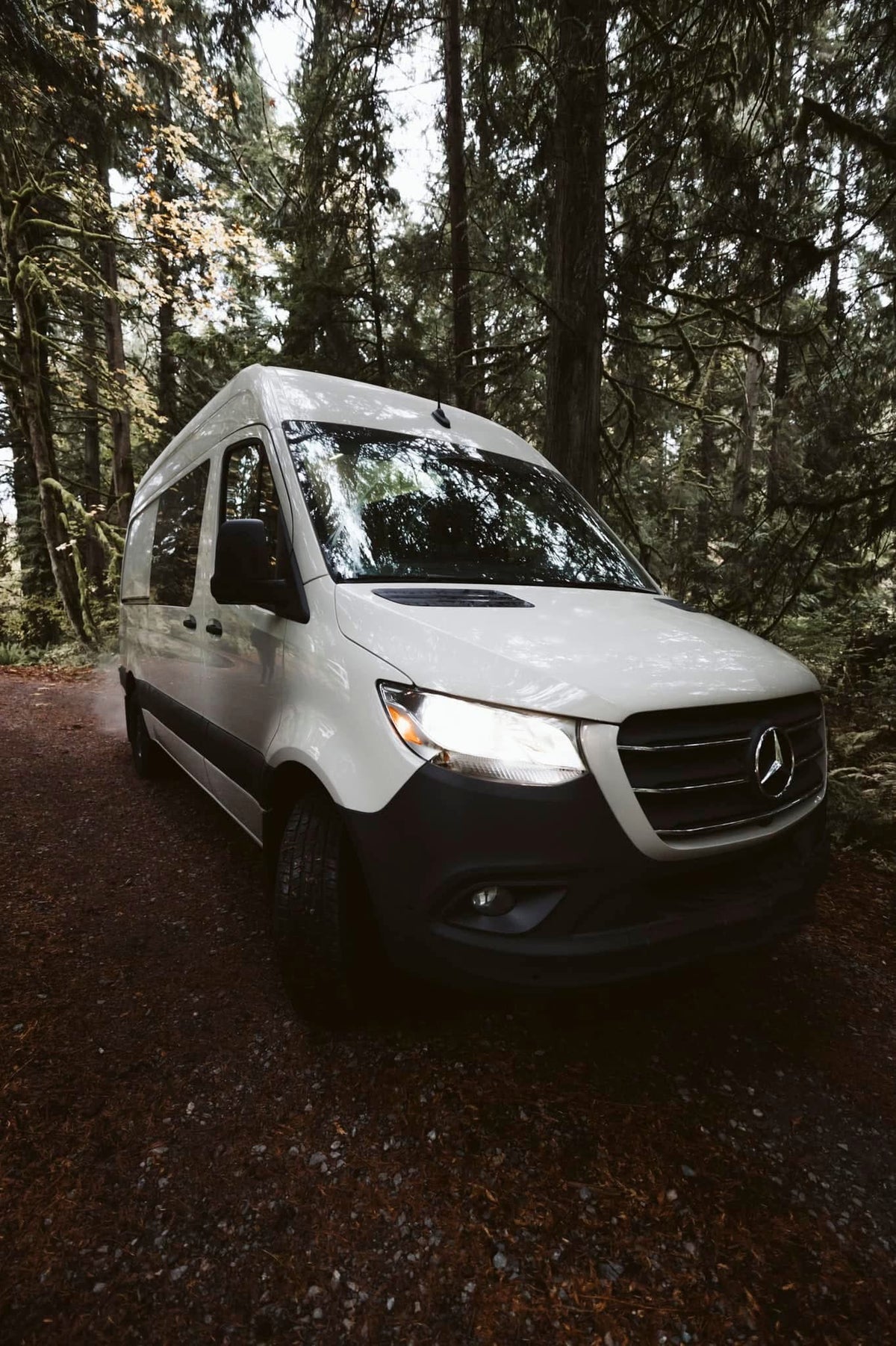White Mercedes Sprinter van with headlights on