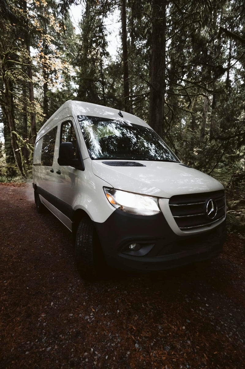 White Mercedes Sprinter van with headlights on — photo 1