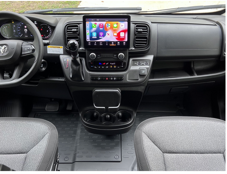 RV rental van interior. Modern dashboard with large touchscreen infotainment, digital cluster, and practical controls. Front seats visible.