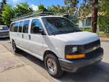 White cargo van with roof rack, a versatile choice for an rv rental conversion, parked on a sunny street.
