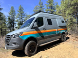 This gray Mercedes Sprinter RV rental, with "Rent RVs online" text, is ready for off-road adventure among pine trees.