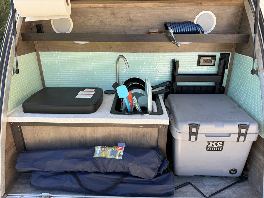Explore this RV rental's convenient outdoor kitchen, complete with a sink, griddle, and K2 cooler, ready for your camping adventures.