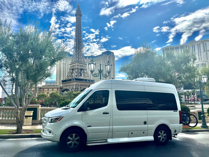 White RV rental van parked on a sunny day in Las Vegas, with the iconic Eiffel Tower replica and hotel buildings in view. — photo 3