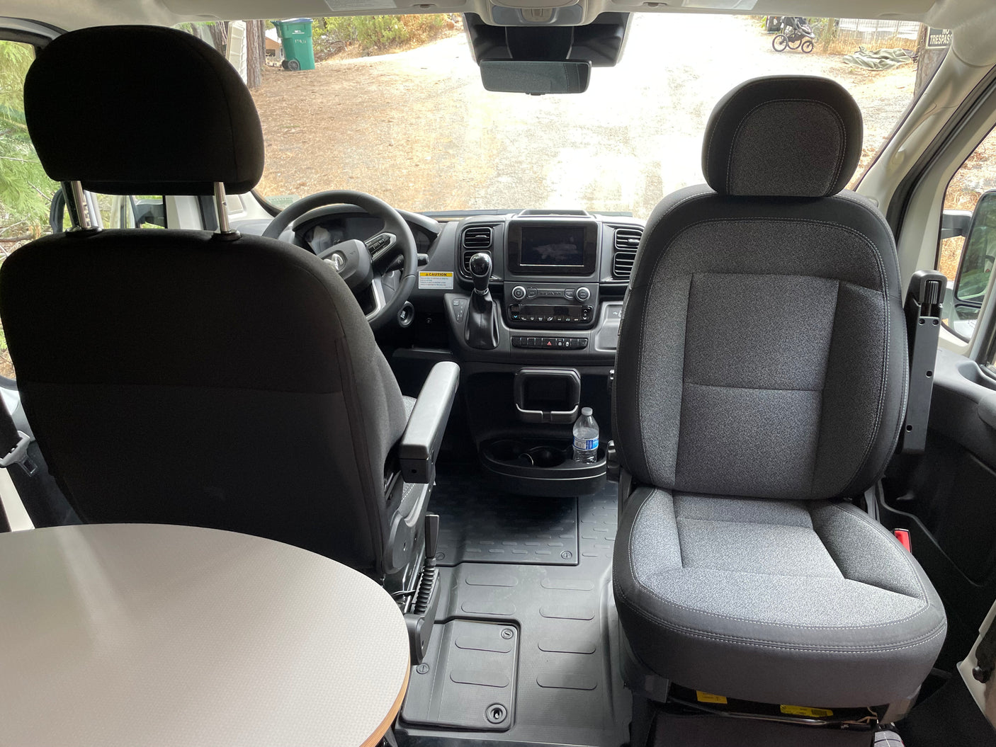 RV rental interior: Driver's cabin with dashboard, comfy front seats, and a small table in the foreground. Perfect for travel.