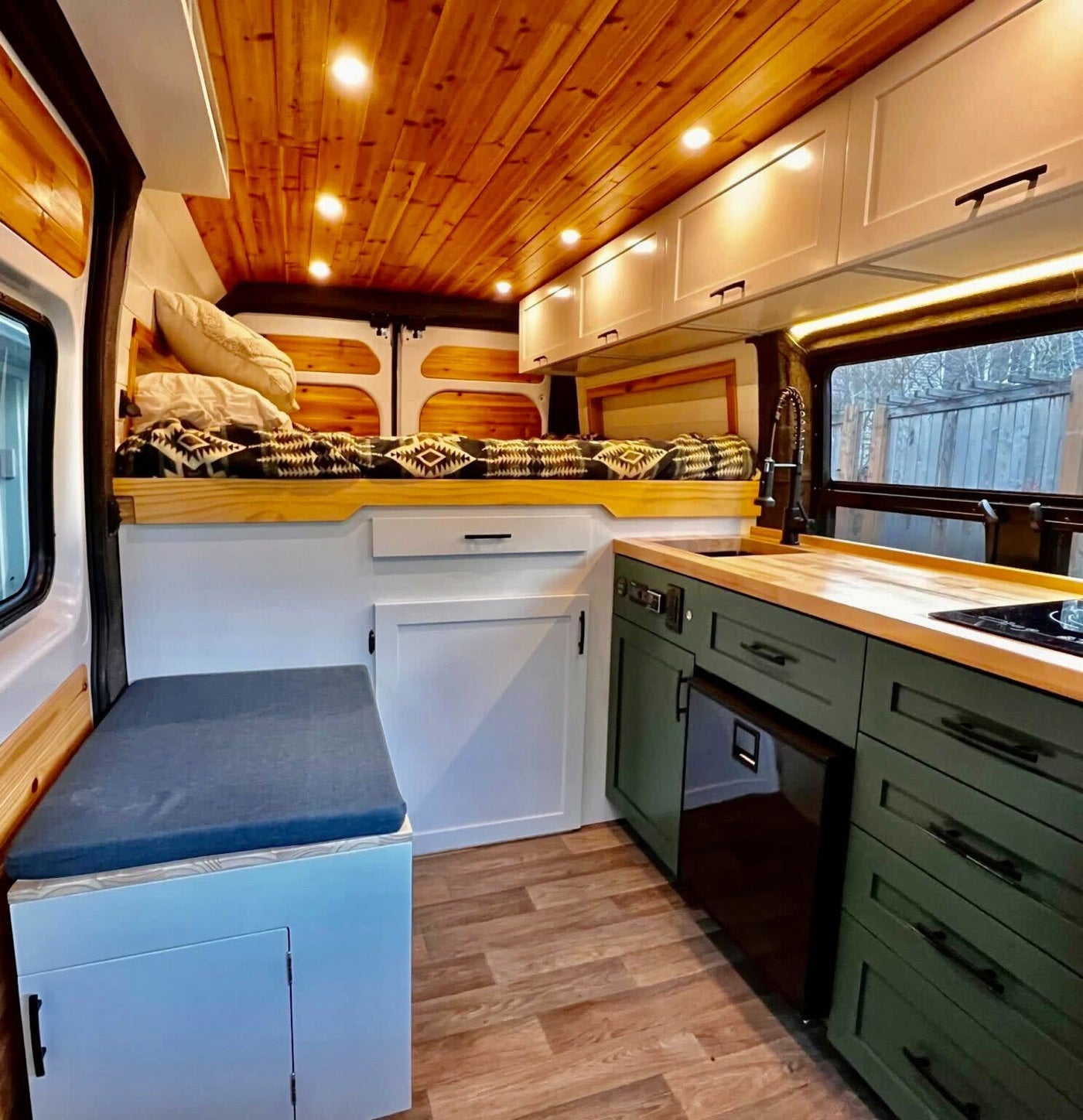  showcasing an inviting interior in a serene forest setting.|Experience comfort in this RV rental! Features a cozy bed — photo 1