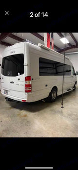 White Mercedes-Benz Sprinter camper van, ideal rv rental. Shown indoors from rear, with tow hitch and side awning for travel.