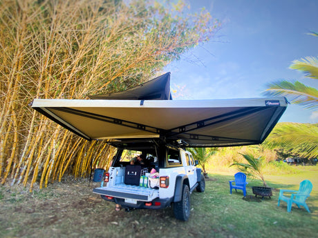 This white Jeep Gladiator, an RV rental alternative, features a rooftop tent & awning for comfortable camping by bamboo.