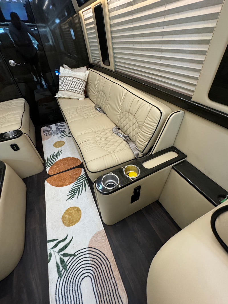 Luxury RV rental interior: comfortable beige bench seating with seatbelts, cup holders, charging port, and decorative rug. — photo 6