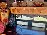 Inside an RV rental: a practical kitchenette with pump, built-in storage, and bright window views. Perfect for travel.