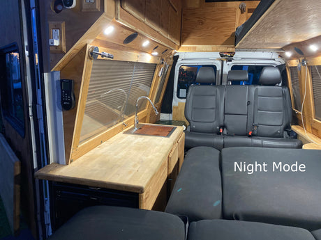 Inside a custom camper van: wooden kitchen with sink, storage, convertible seating/bed, and LED lights. Great for RV rental road trips.
