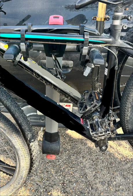 A dirty mountain bike with knobby tires is securely mounted on a Yakima bike rack, ready for an RV rental outdoor adventure.