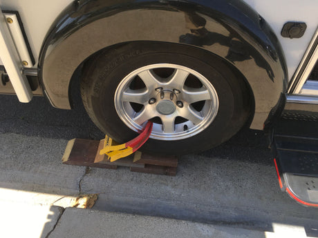 Close-up of an RV rental wheel, securely chocked on wooden blocks for stable parking and safe travel.